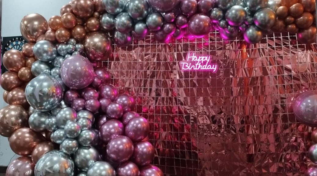 Photocall con globos rosa y plata y con feliz cumpleaños en luces de neón